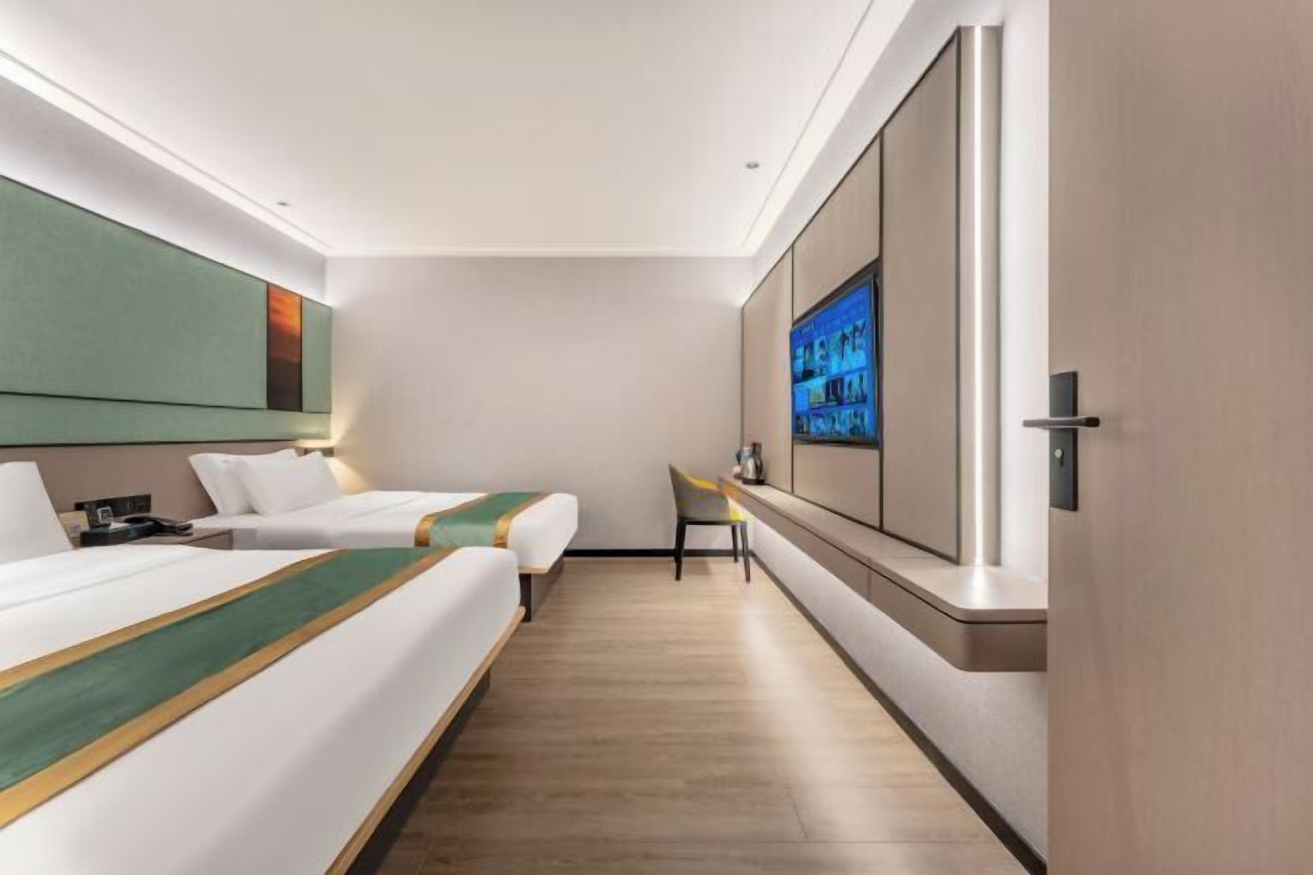 Habitación de hotel con dos camas, televisor, escritorio y un espejo grande.