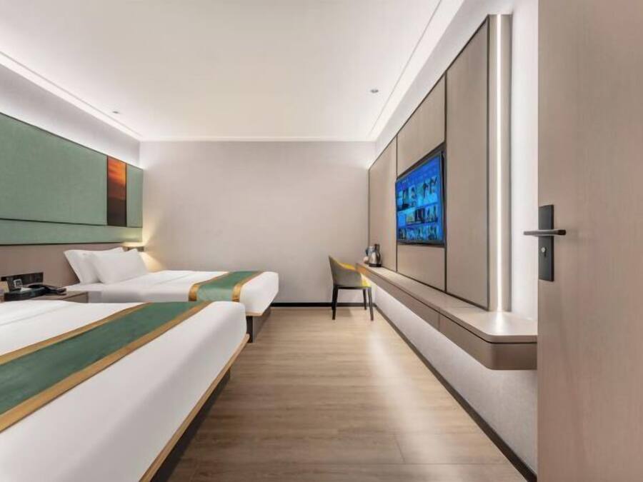 Une chambre d’hôtel avec deux lits, une télévision, un bureau et un grand miroir.