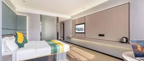 A modern hotel room with a bed, a desk, a TV, and a coffee maker.