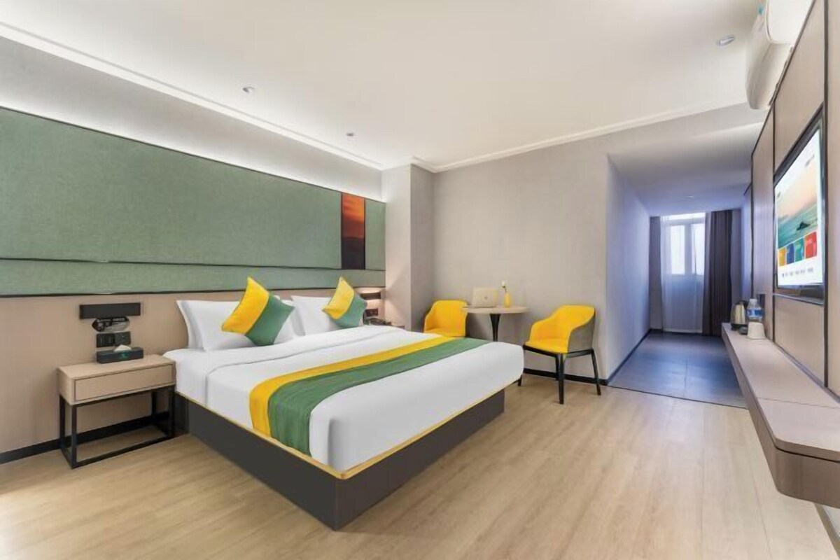 Ein Hotelzimmer mit Bett, Nachttisch, Sesseln, Schreibtisch und Fernseher.