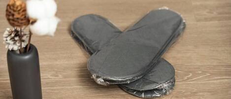 Un par de jeans sobre un piso de madera, con un jarrón negro y flores secas.