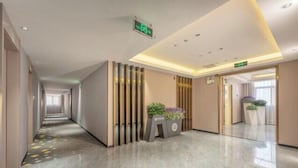 En moderne hotellobby med en lang gang, en reception med planter og en ren, poleret gulv.