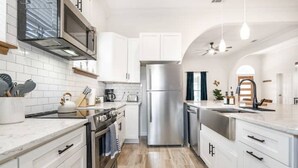 A modern kitchen with white cabinets, stainless steel appliances, and a marble countertop.