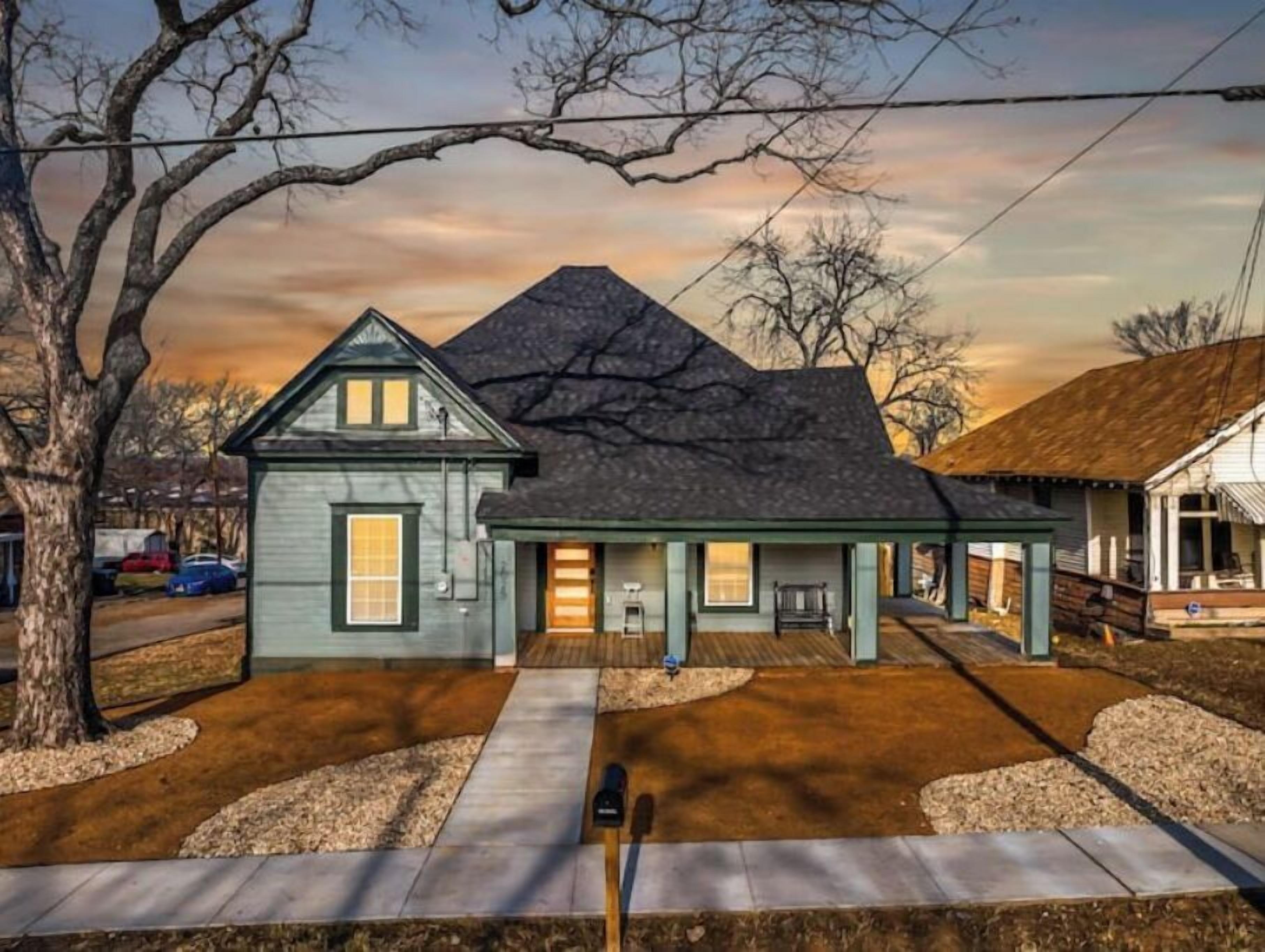 A two-story house with a dark roof, a front porch, and a driveway leading to the entrance.