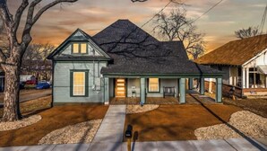 A two-story house with a dark roof, a front porch, and a driveway leading to the entrance.