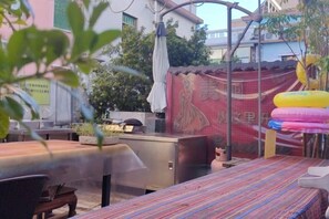 An outdoor patio with a grill, tables, and a colorful striped tablecloth.