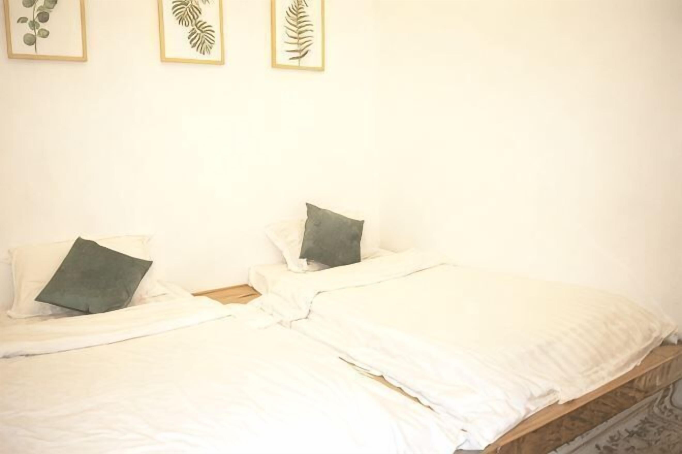 A room with two beds, each with a pillow and a framed leaf decoration on the wall.