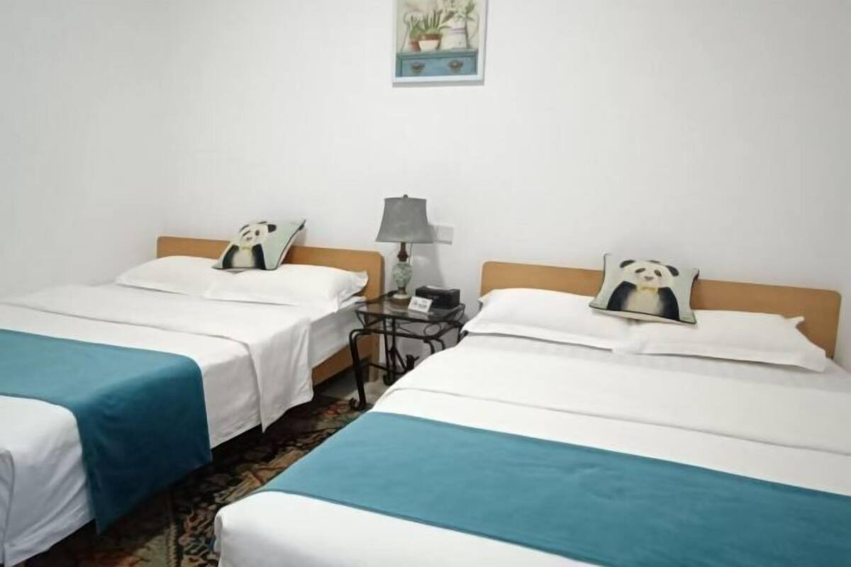 Une chambre d’hôtel avec deux lits, une table de chevet avec une lampe et un tableau accroché au mur.