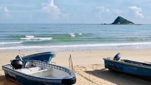 Two boats on a sandy beach with calm water and a distant island. - Mr. Peng Inn (Shenzhen)