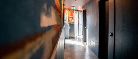 A corridor with a polished floor, a door on the right, and a sign indicating an exit.