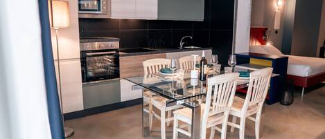 A modern kitchen with a glass dining table and white chairs, a built-in oven, and a microwave.