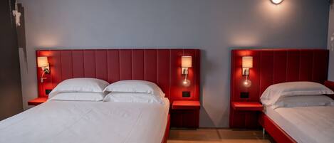 Une chambre d’hôtel avec deux lits, chacun doté d’une tête de lit rouge et de lampes de chevet.