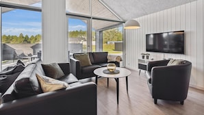 A modern living room with a large TV, comfortable seating, and a view of the outdoors. - Gorgeous home in Rømø with sauna (Rømø)