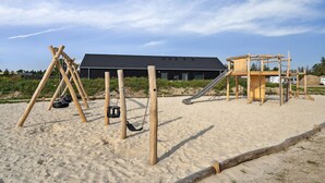 A sandy beach playground with swings, a slide, and a climbing structure. - Gorgeous home in Rømø with sauna (Rømø)