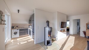 Una cocina moderna con lavadora integrada, estufa y mesa de comedor de vidrio.