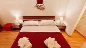 A hotel room with a large bed, two nightstands, a red throw blanket, and two towels on the bed. - 1 bedroom beautiful apartment in Firenze (Firenze)