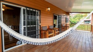 Une terrasse en bois avec un hamac, une table et des chaises.