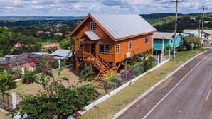 Une maison en bois avec un toit en métal, un escalier et un jardin clôturé.