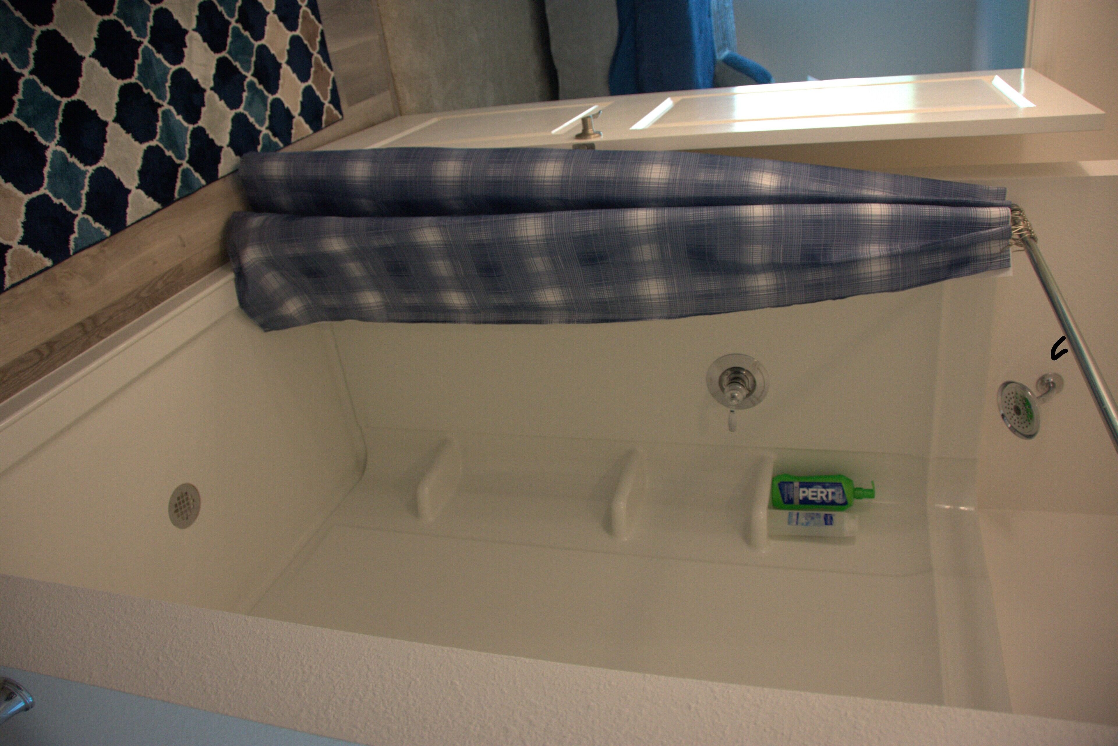 A bathtub with a blue and white checkered towel, a toothbrush, and a bottle of mouthwash.