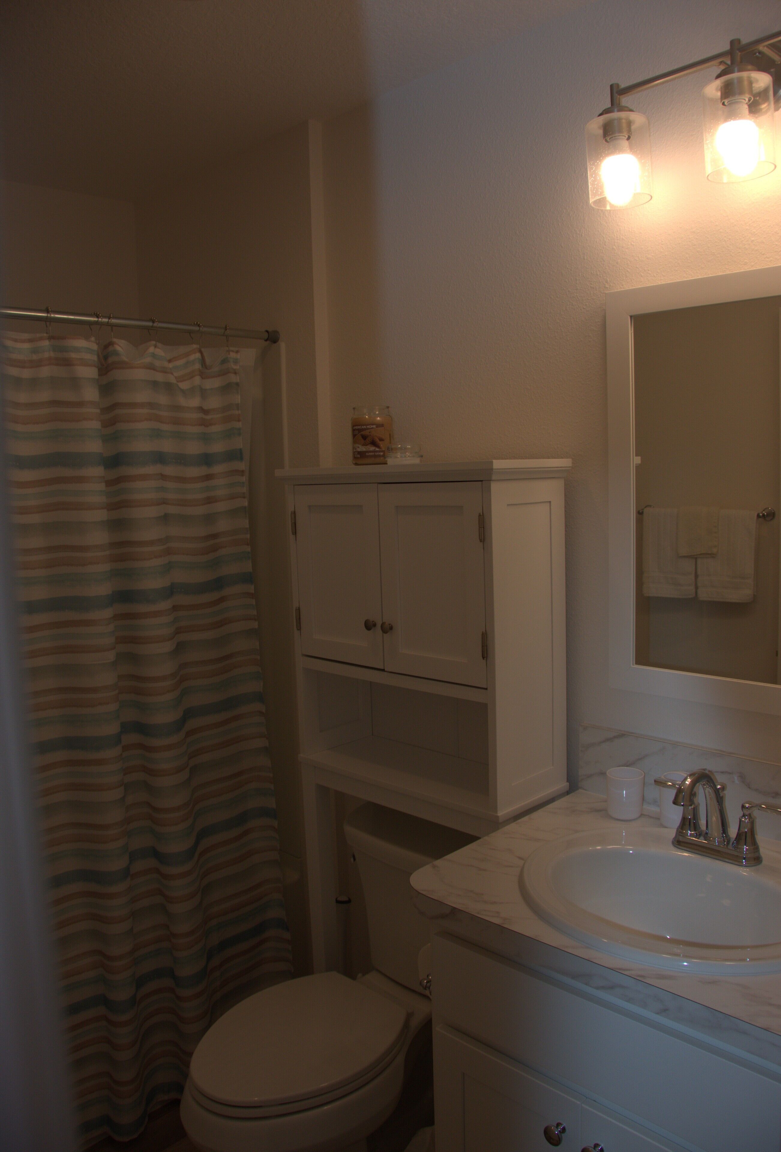 A bathroom with a toilet, a sink, a mirror, and a shower curtain.