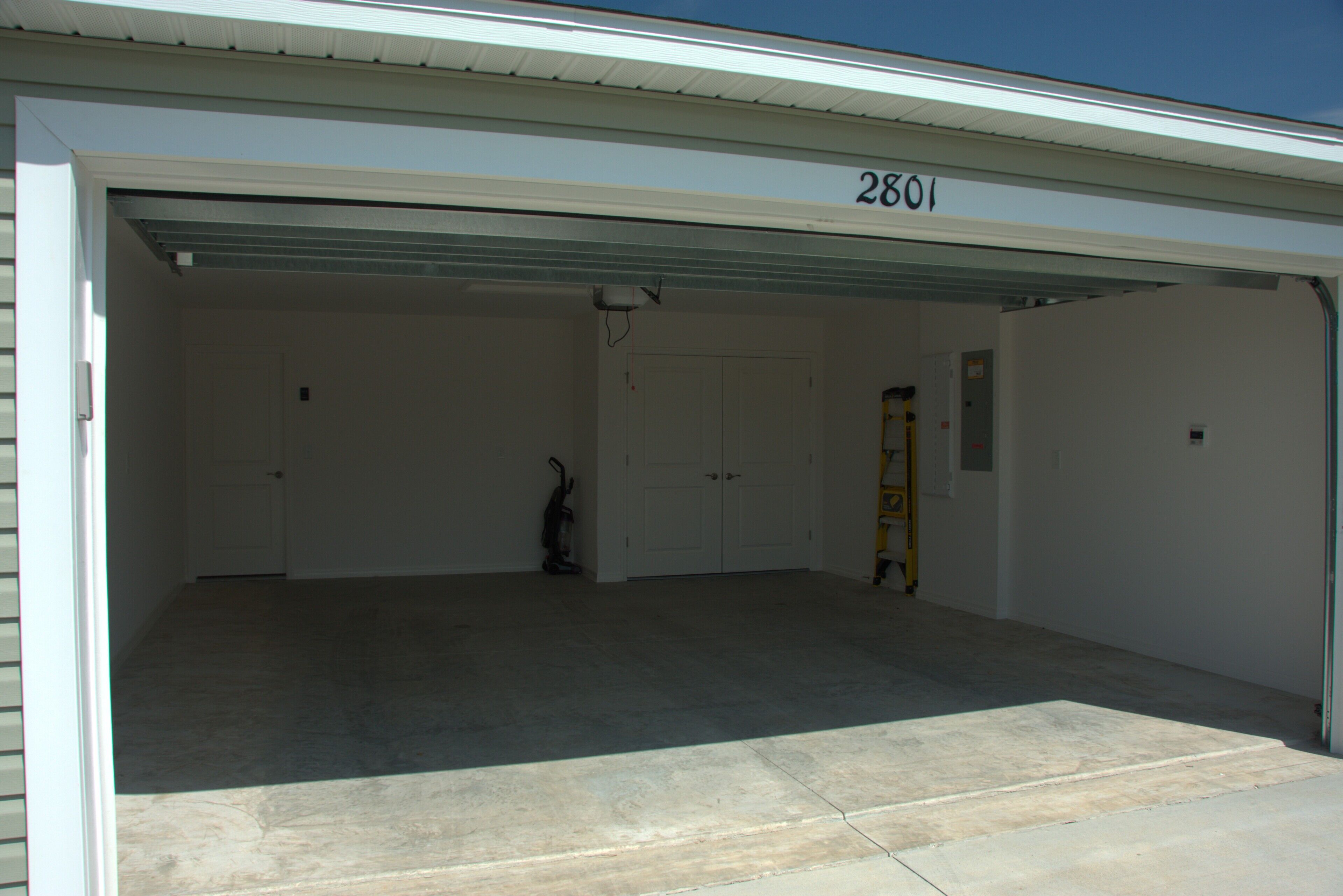 En garage med et rent, tomt interiør, nummer 2801 på garagedøren, og en stige lænet op ad væggen.