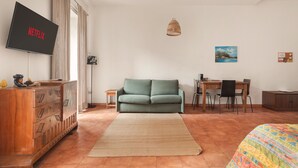 A modern living room with a flat-screen TV, a sofa, a dining table with chairs, and a hanging light fixture. - Marina Square Open Space (Palermo)