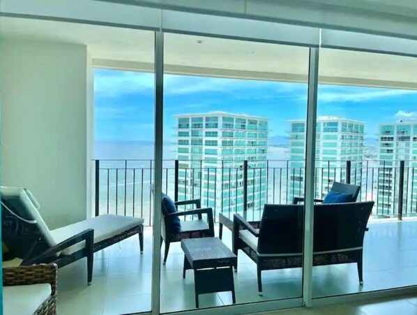 A balcony with a view of high-rise buildings and the ocean.