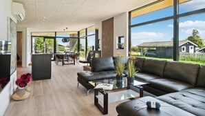A modern living room with a leather sofa, glass coffee table, and a view of the outdoors. - Gorgeous home in Skibby with kitchen (Skibby)