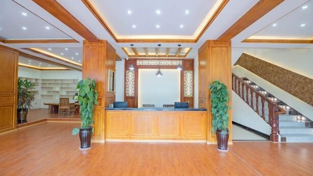 A reception area with a wooden reception desk, potted plants, and a staircase. - Jiayuan Boutique Hotel (Gongshan)