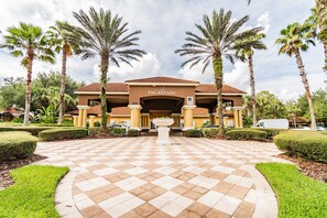 Welcome to Encantada, where a central pathway leads to the main entrance, flanked by palm trees and hedges.