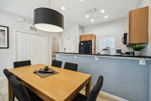 A modern kitchen with a central island, white cabinetry, and a black refrigerator. - Encantada 2-Suite Home Near Disney w/ Free Hot Tub (Kissimmee)