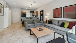 Un salon moderne avec un canapé gris, une table basse et une cuisine en arrière-plan.