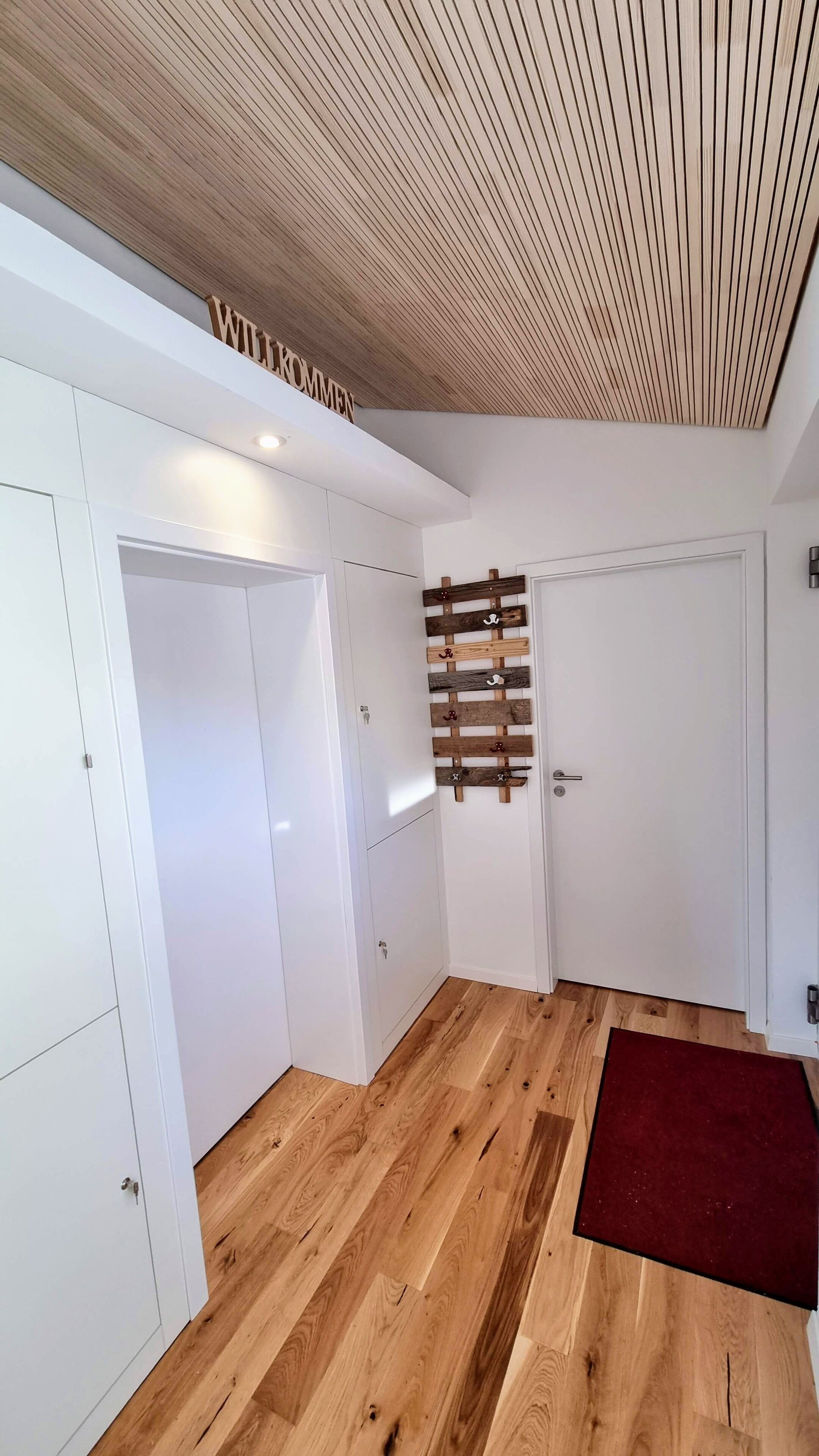 Een modern interieur met witte muren, houten vloeren en een plafond met een gebonden lambrisering.