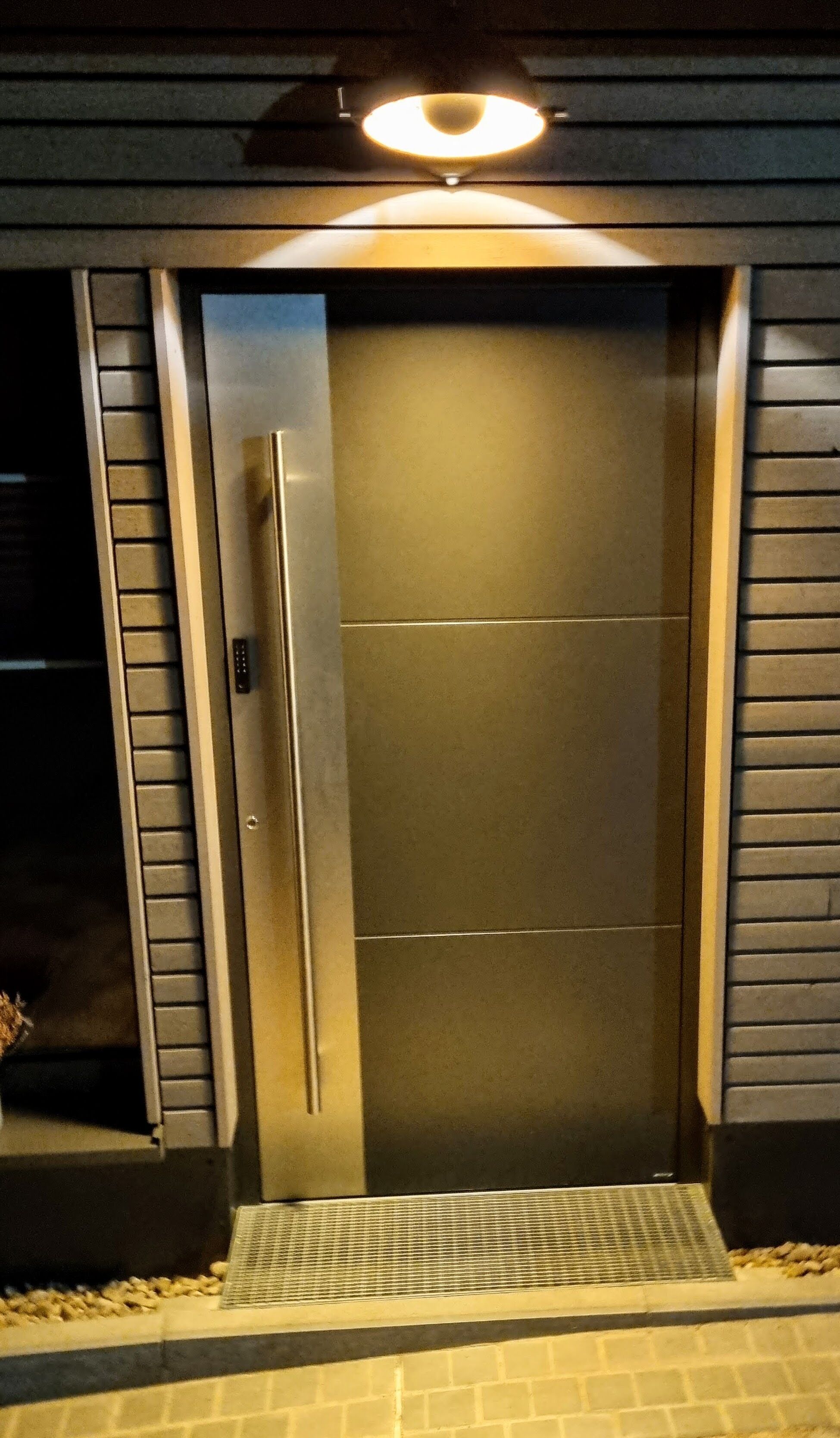 A modern entrance with a metallic door and a small step leading up to it.