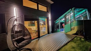 A modern building with a wooden deck, a hanging chair, and a green bus-like structure with "GBAHN Kur" visible. - Exclusive House with old Mountain-Railway (Baden-Baden)