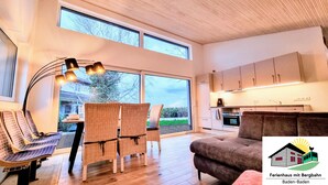 A modern living room with a large window, wicker furniture, and a cozy sofa. - Exclusive House with old Mountain-Railway (Baden-Baden)
