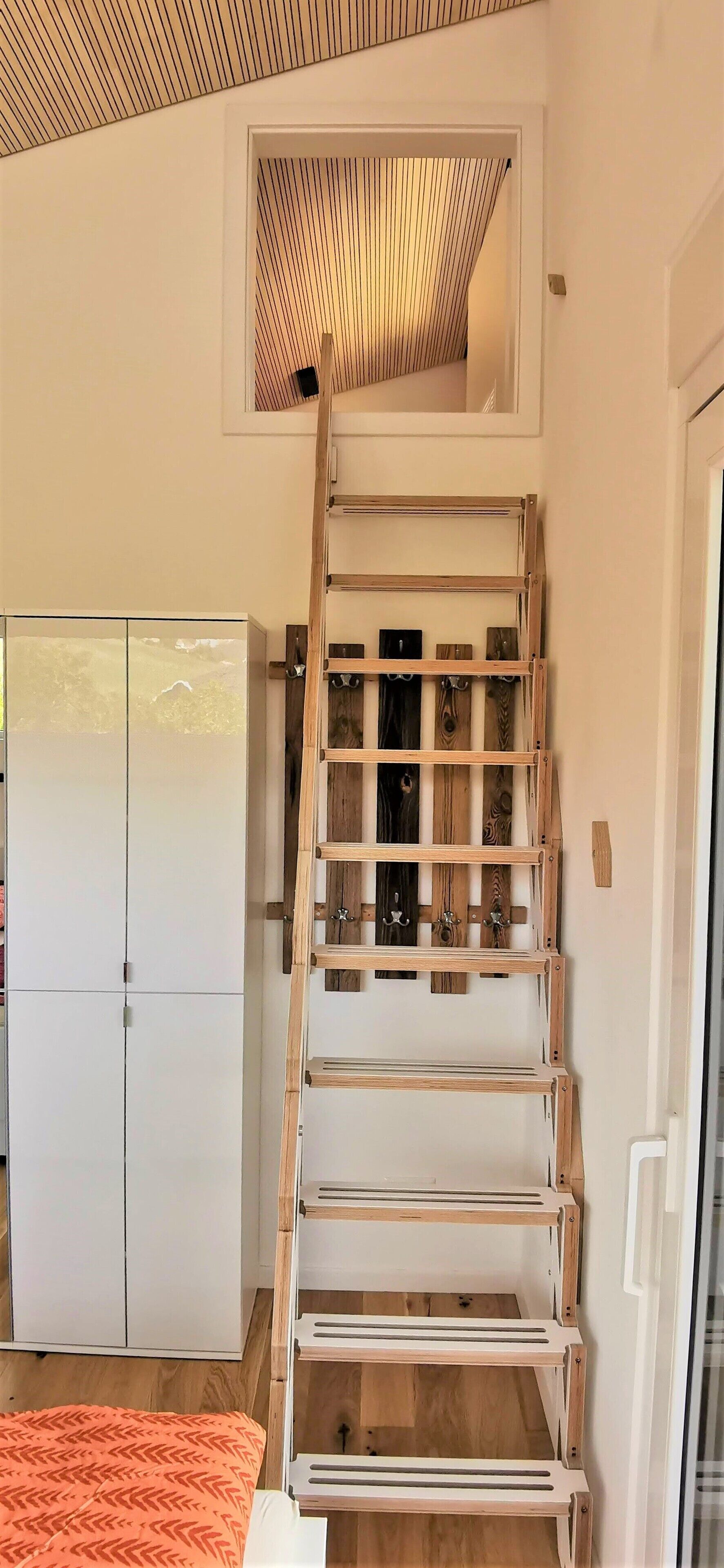 Een kamer met een houten ladder, een kledingkast en een bed.