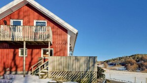 Un edificio rojo con balcón, cerca de madera y paisaje nevado.