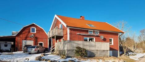 A red two-story house with a sloped roof, a garage, and a visible satellite dish.