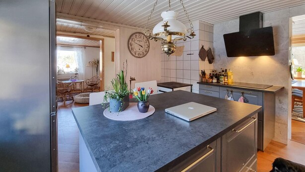 Una cocina moderna con una encimera oscura, una computadora portátil y una planta en maceta.