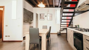 A kitchen with a dining table, chairs, a staircase, and an oven.