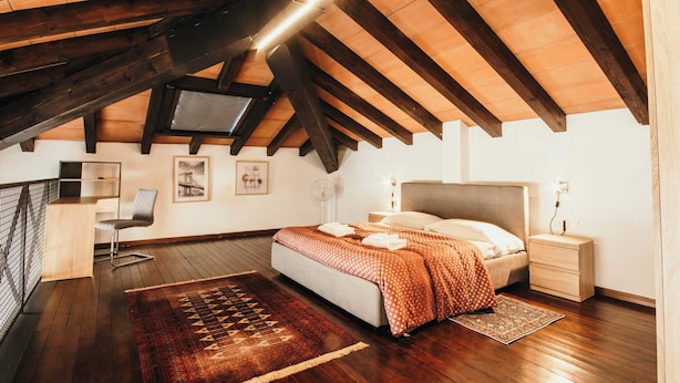 A bedroom with a bed, nightstand, and a TV mounted on the ceiling.