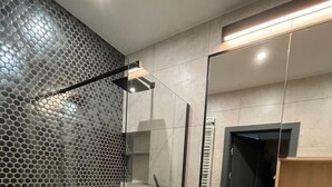 A modern bathroom with a glass-enclosed shower, a white sink, and a large mirror. - Poznan Surburb Apartament (Skórzewo)
