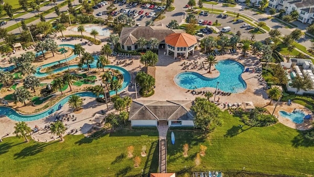 Ett flygbildsfoto av ett semesterområde med flera pooler, en huvudbyggnad och omgivande grönska.