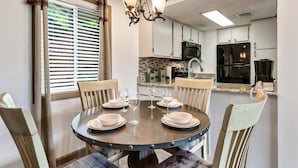 A dining area with a round table, chairs, and a chandelier. - Deer Ridge Resort C207 - Amazing Mountain Views, Pool, and Tennis (Gatlinburg)