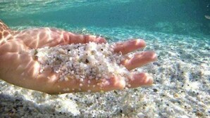 A hand holding small white pebbles over a sandy seabed. - Vacation Home Il Gelsomino-5 minutes from the beach (Siniscola)