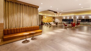 A spacious lobby with a modern design, featuring a seating area with a sofa and chairs, a reception desk, and a large window offering a view. - Ondas Praia Resort by WAM Experience (Porto Seguro)