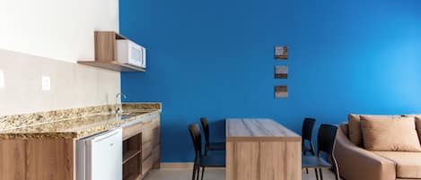 A modern kitchen with a built-in microwave, a dining table with chairs, and a sofa.