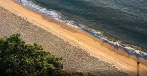 A beach with a clear view of the ocean, a sandy shore, and a line of trees in the foreground. - Ondas Praia Resort by WAM Experience (Porto Seguro)