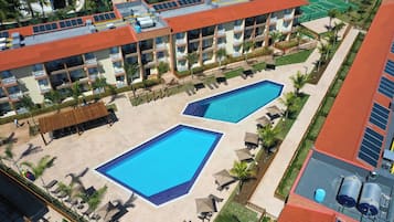 Hotel com duas piscinas, várias varandas e um terraço com painéis solares.